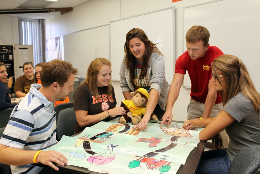 Students gathering and looking at teaching materials for young students