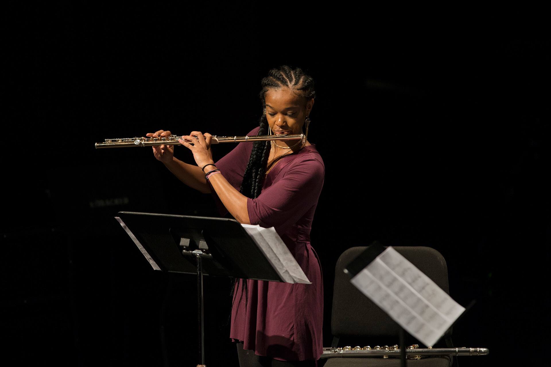 A student playing the flute and looking at sheet music.