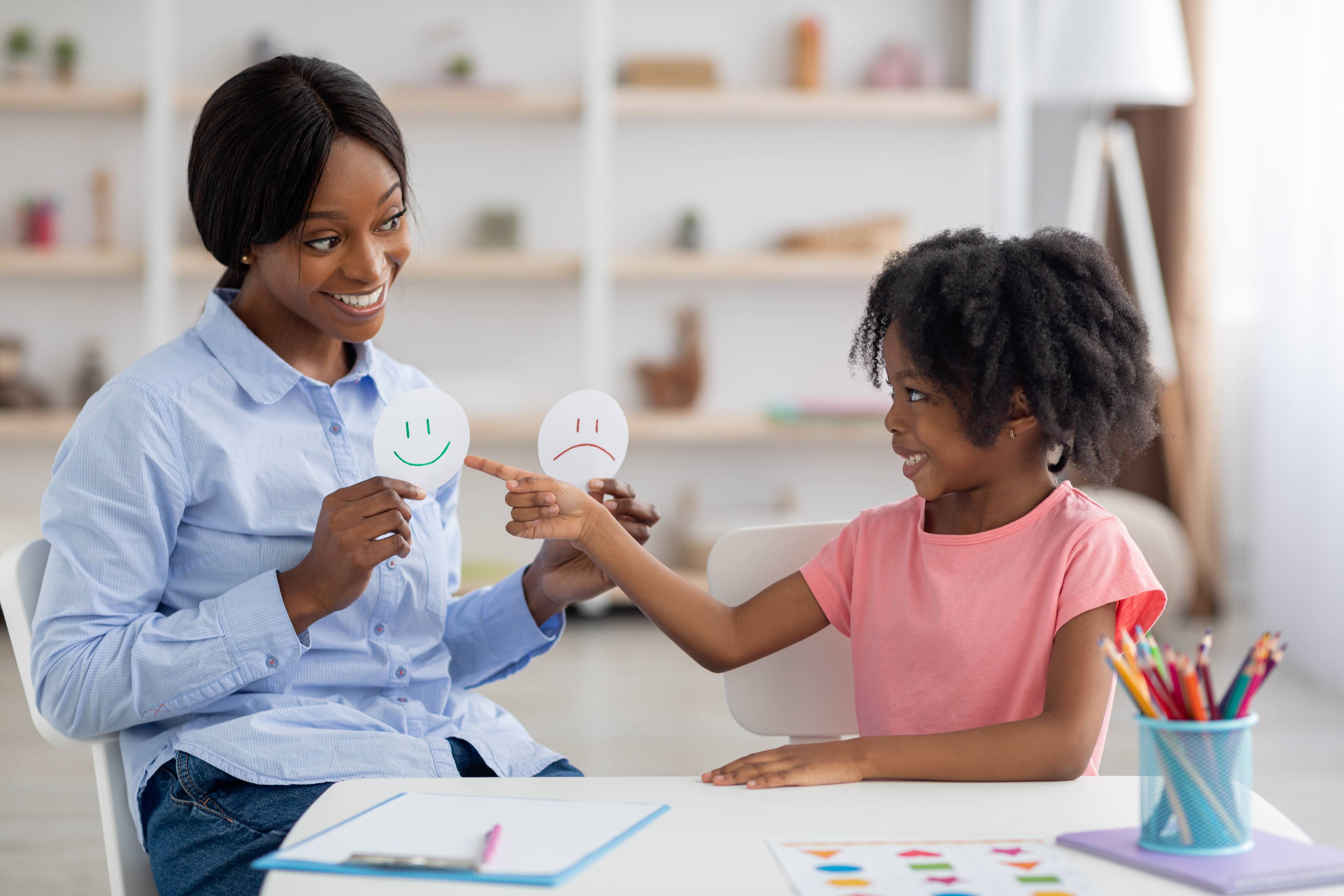 Female teacher and little black girl exercising at daycare