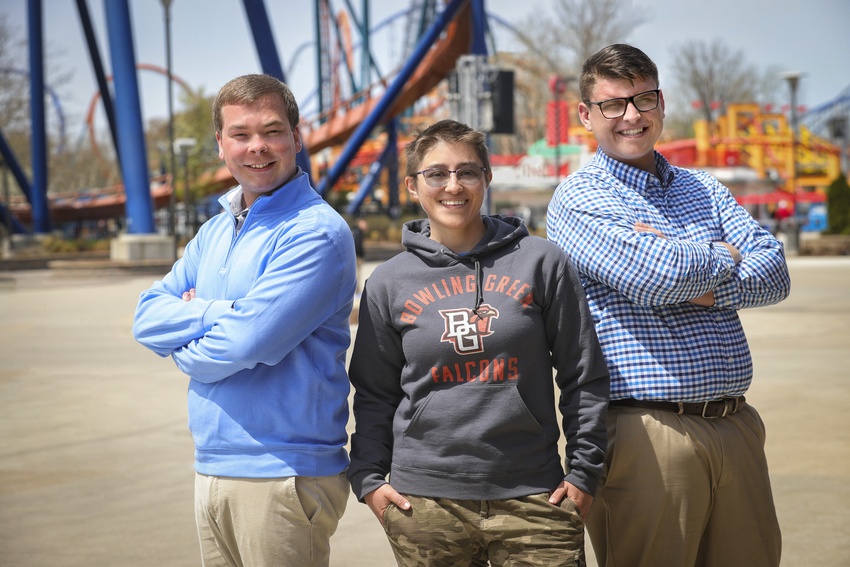 3 people standing in front of roller coasters and attractions at Cedar Point