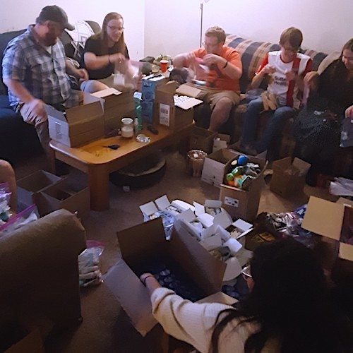 several graduate students sit on couches assembling care kits with toiletry items