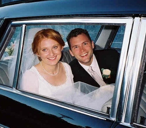 Two people smiling out the window of a car