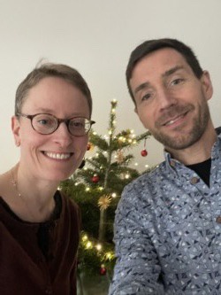 Two people smiling in front of a christmas tree