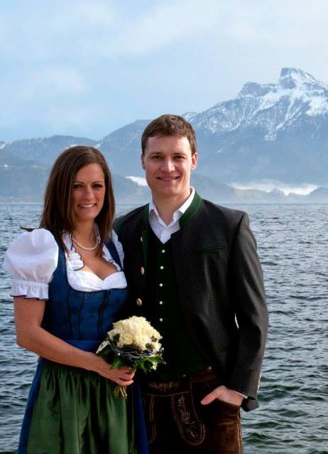 Two people posed in front of water and a mountain