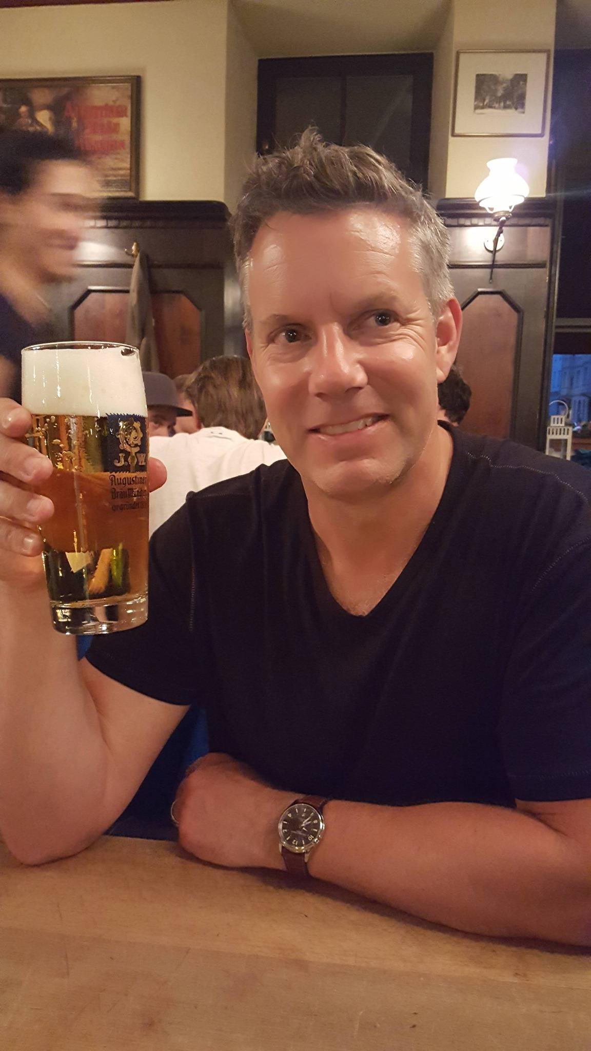 A man sitting at a bar and holding a beer