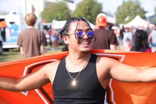 A man smiles while draped in a BGSU flag