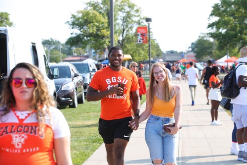 A man and woman hold hands while walking