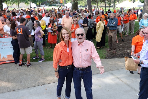 Two people smile and hug each other with a large crowd behind them