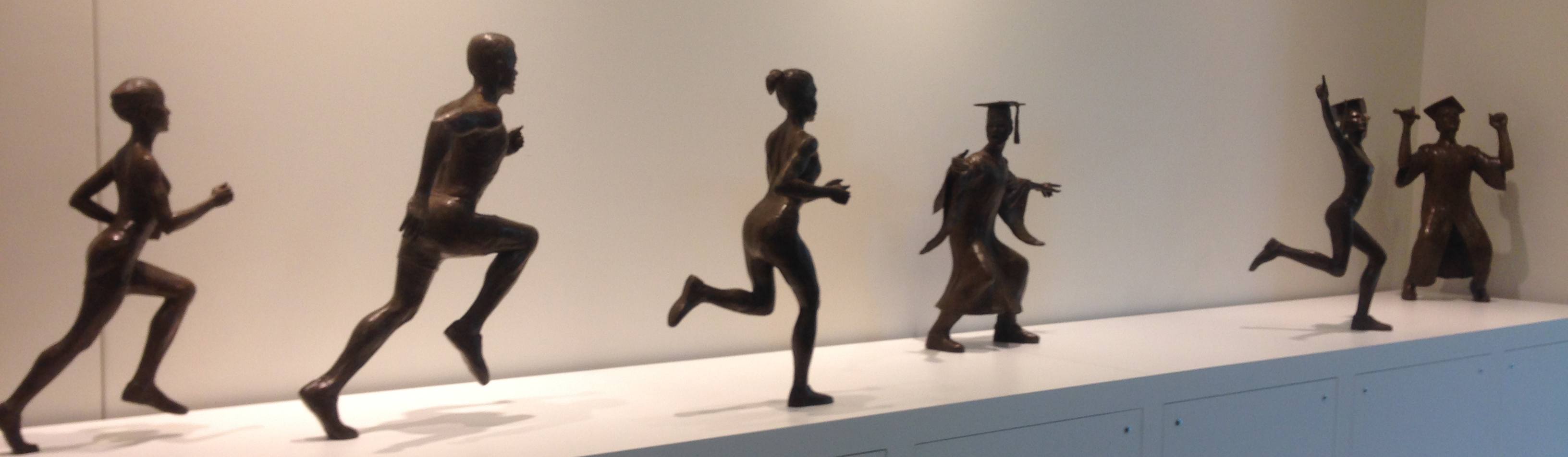 Sculpture located at NCAA headquarters in Indianapolis showing student-athletes running and culminating with student-athlete in cap and gown at graduation.