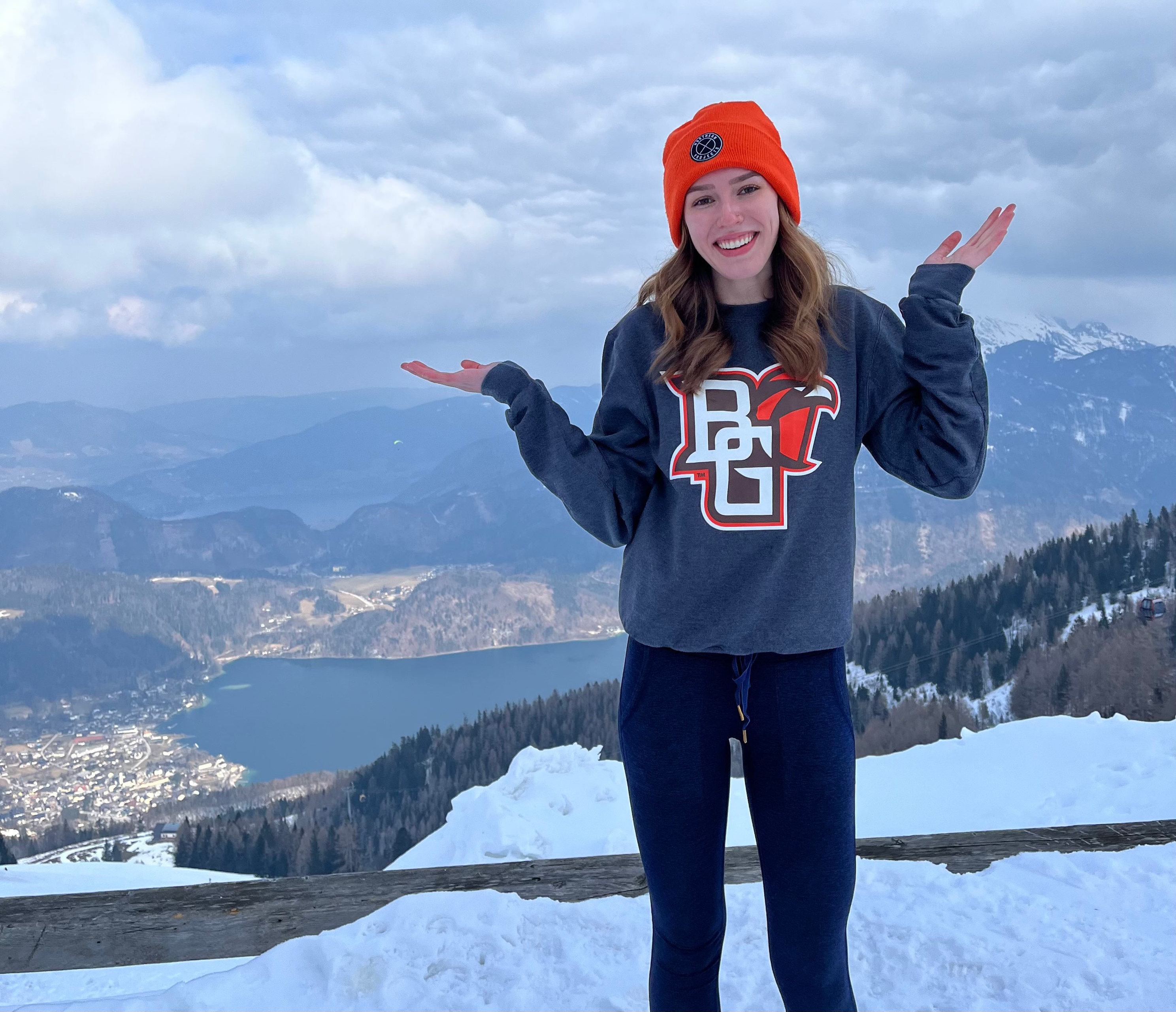 A person wearing a BGSU sweatshirt stands on a snowy mountaintop.
