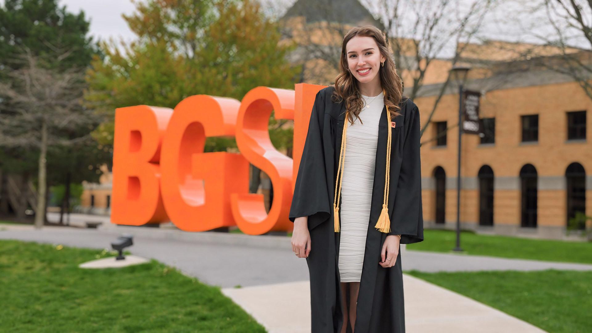 BGSU graduate Bailey Price stands in front of the BGSU letters on campus.