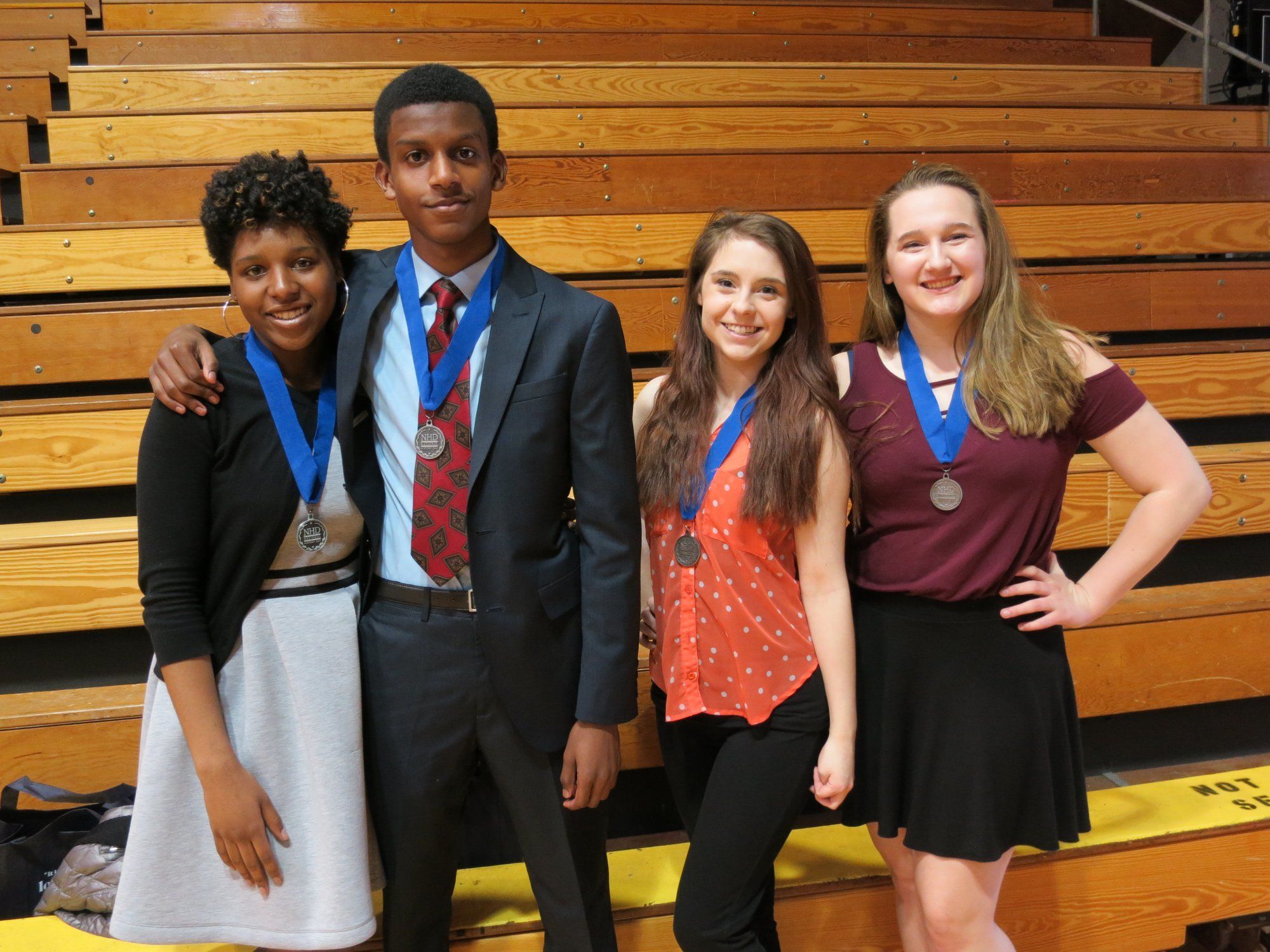 Four students stand together, each with medals around their necks 