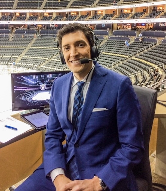 A man wears a headset inside of a hockey arena.