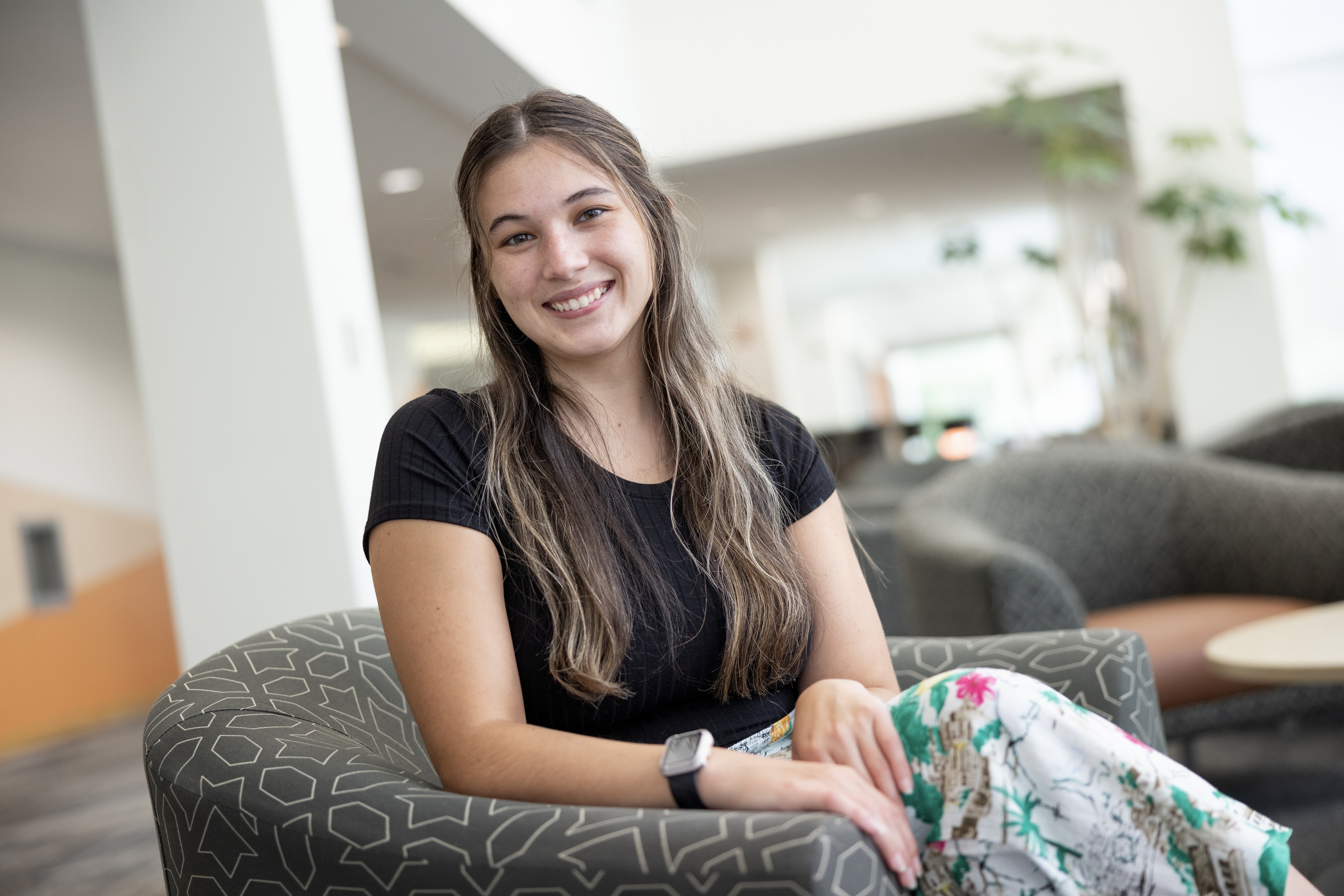 A person smiles while sitting in a chair.