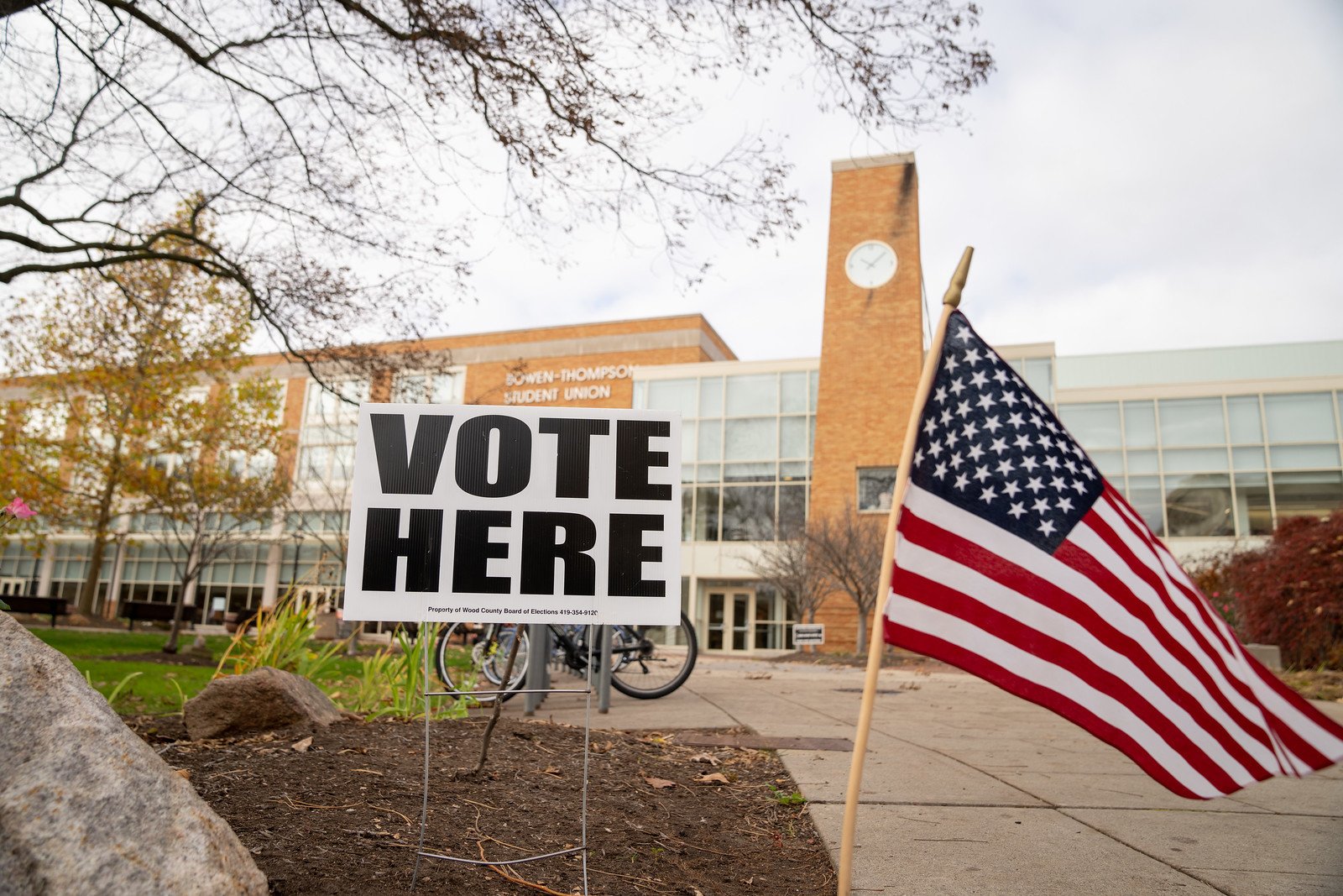 A sign with the words 'Vote Here' next to a small American flag outside the BGSU Bowen-Thompson Student Union. 