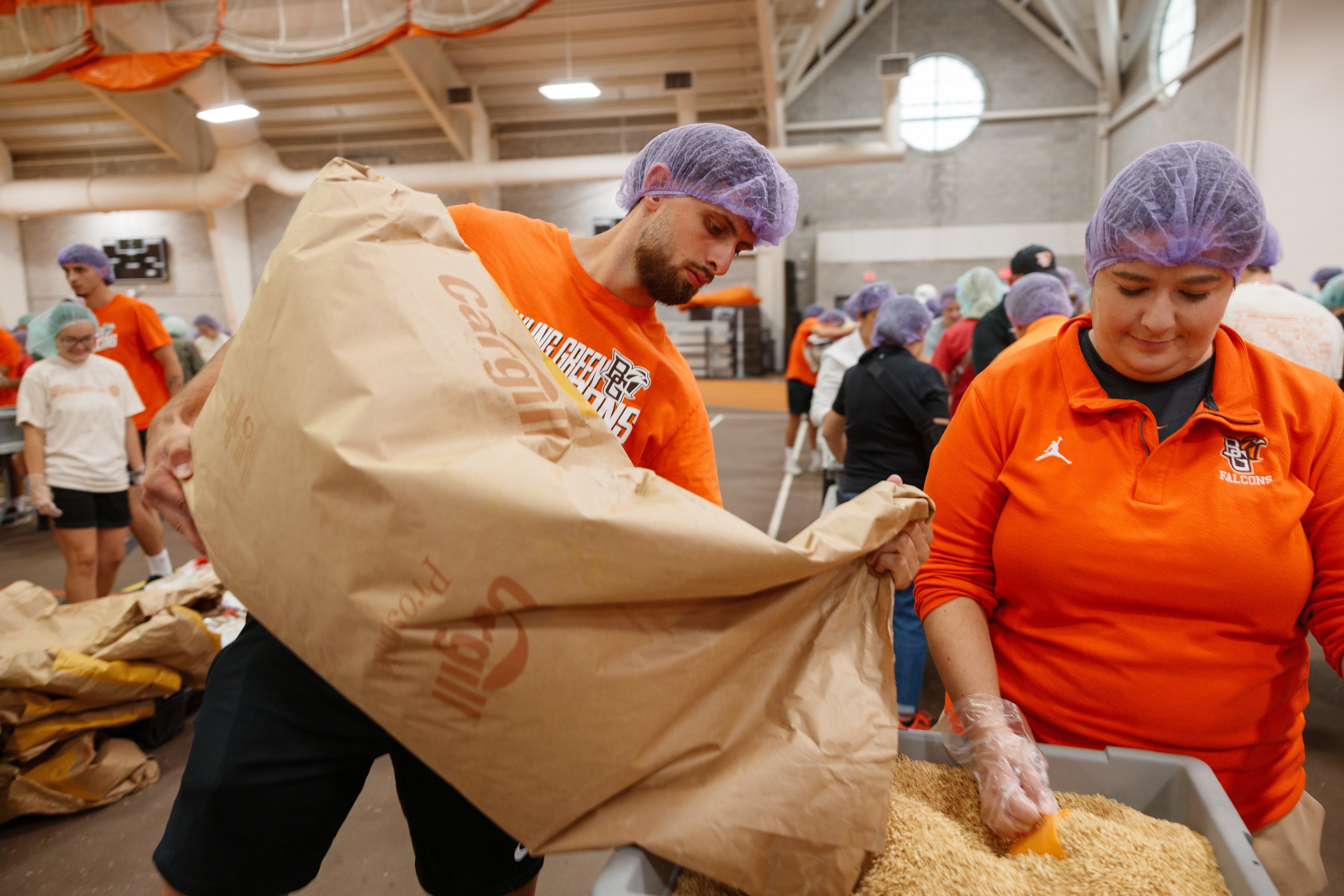 Man in hair net pours bag of food into bin