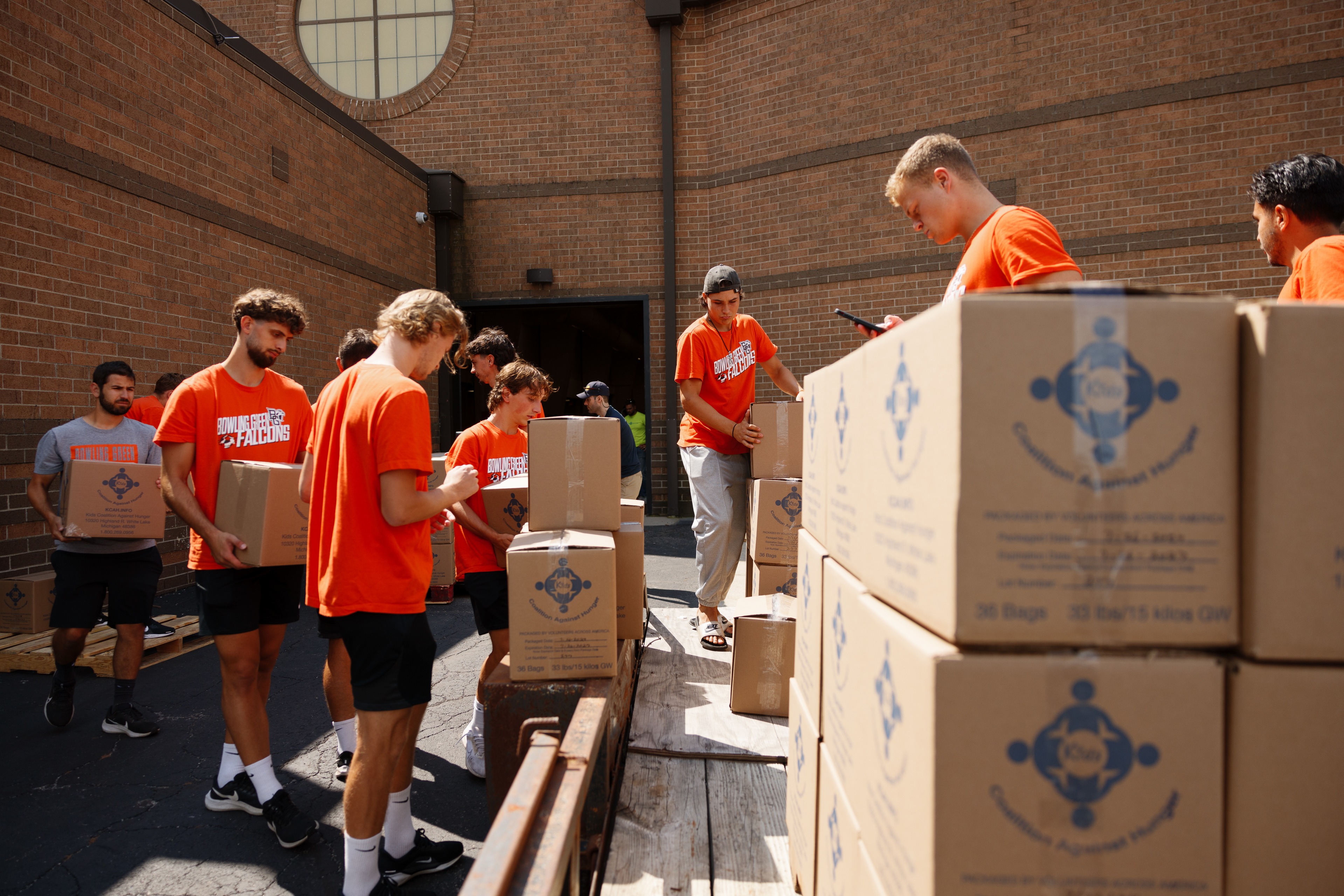 Volunteers load boxes of food packets onto a trailer