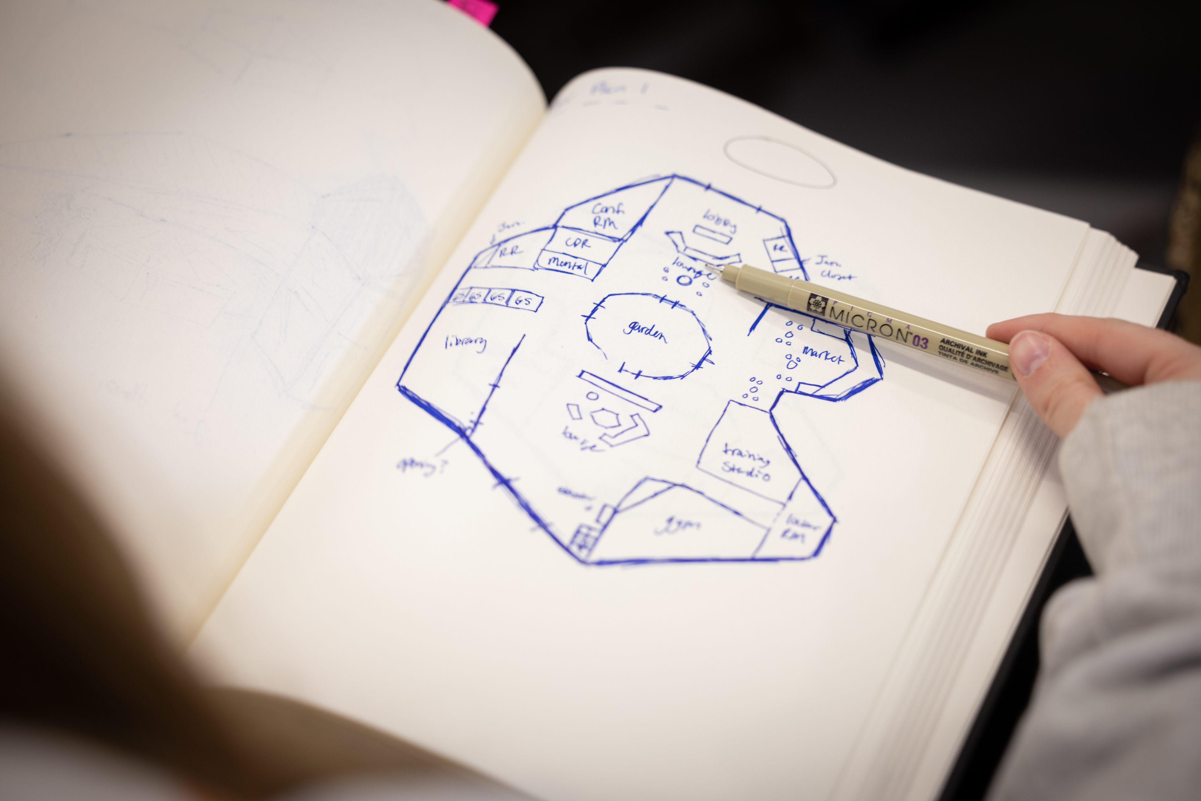 A person draws a blueprint in a notebook.