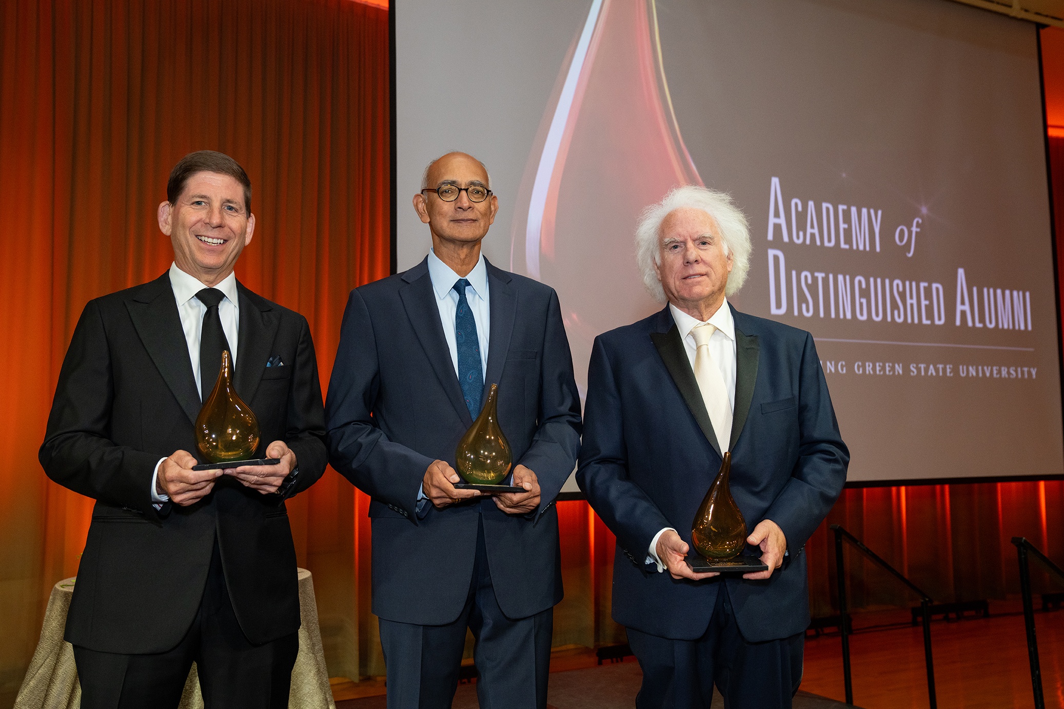 Three men pose for a picture holding awards