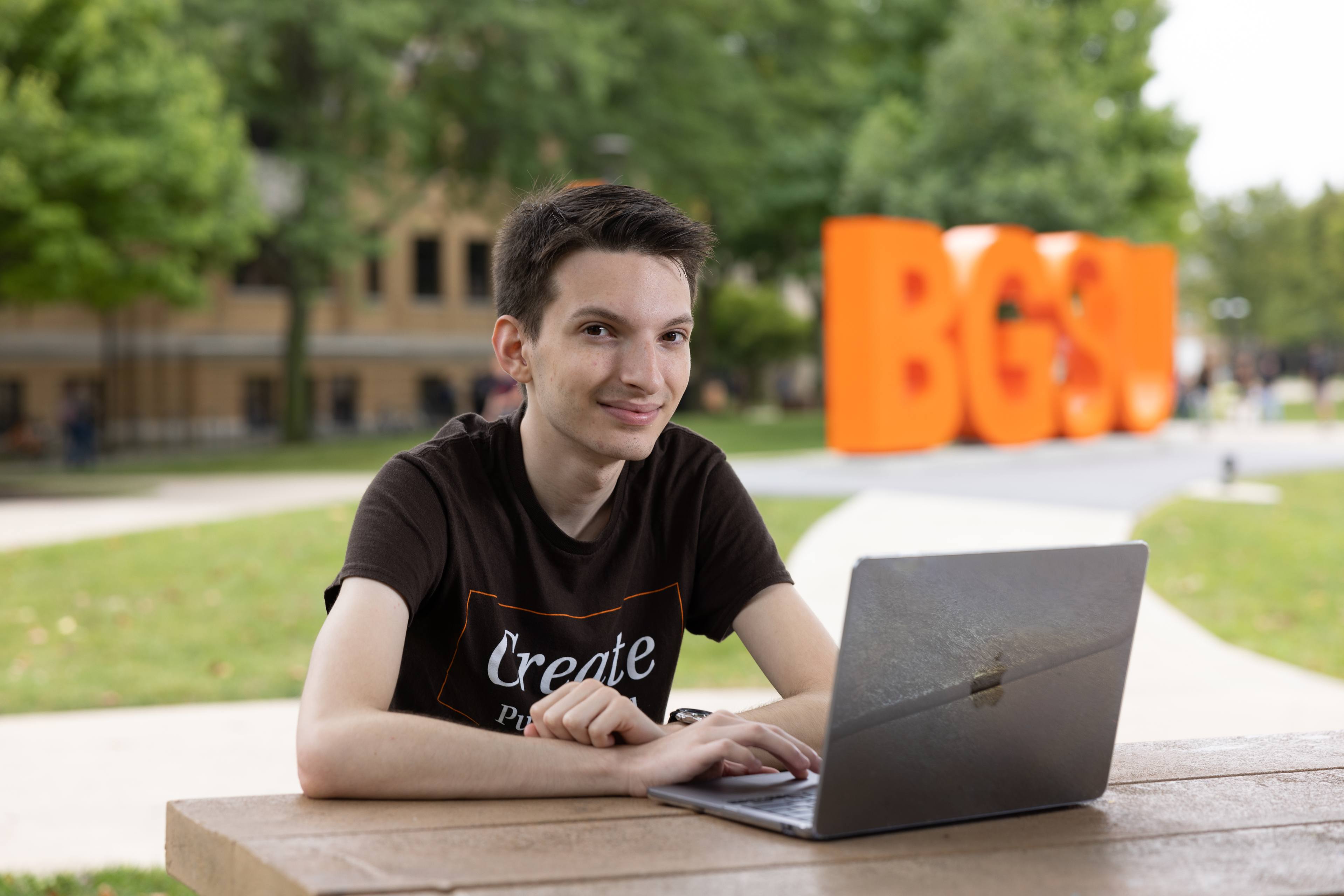 Student poses for picture while on computer