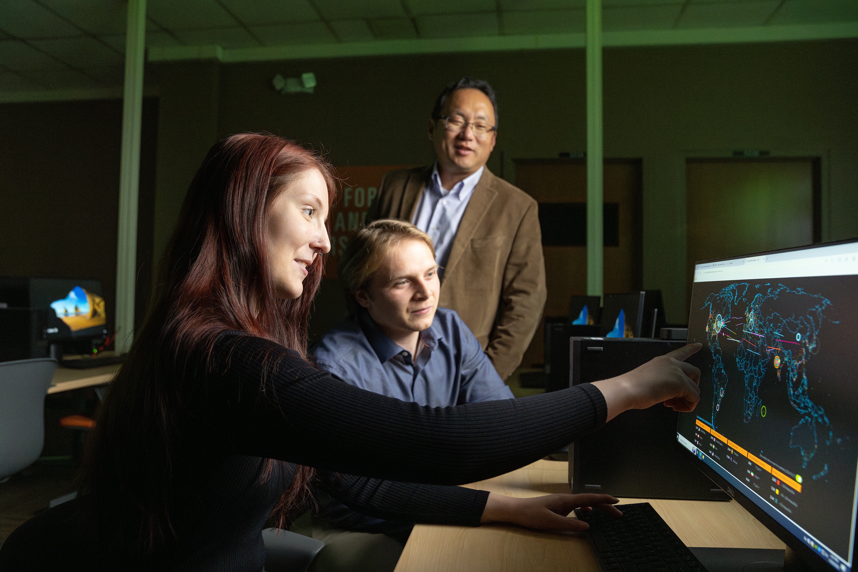 Three people work on a computer