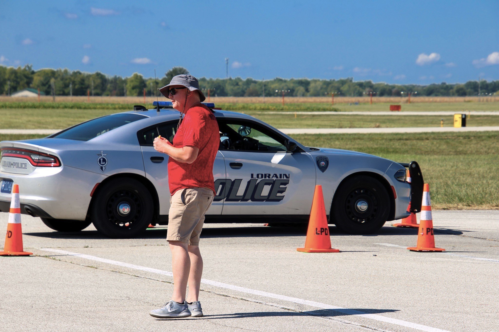 A police officer stands in front a cruiser.