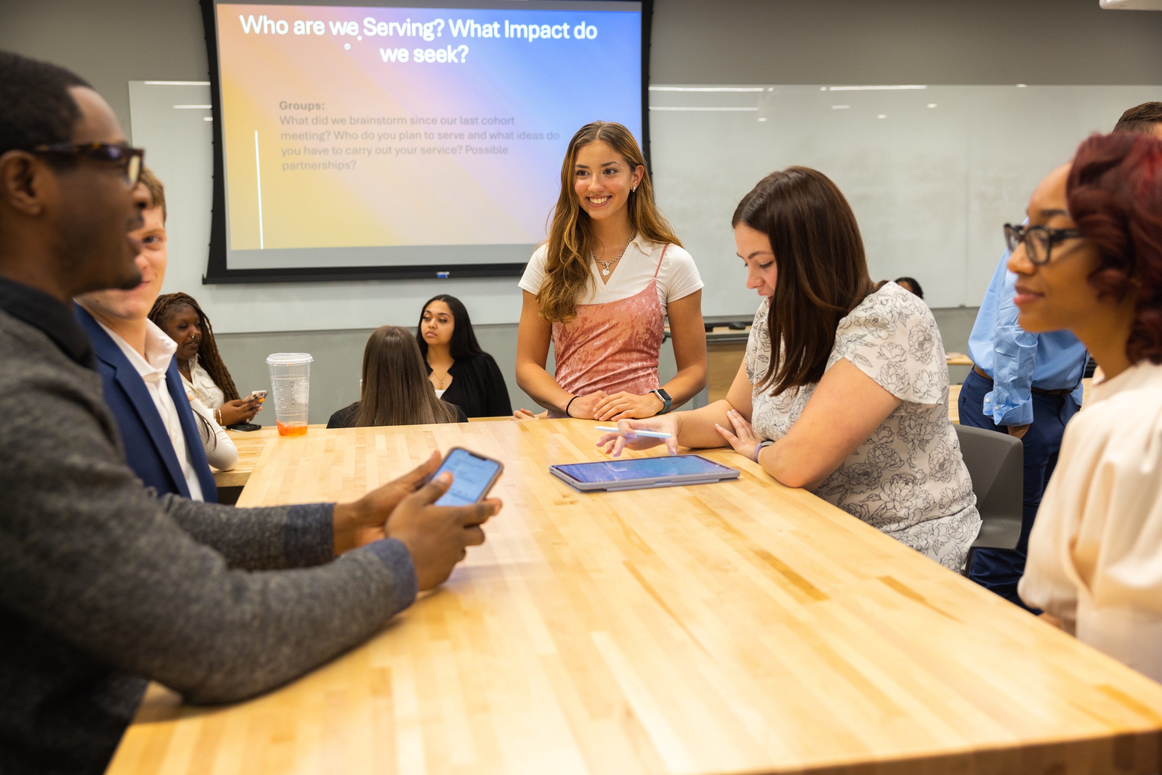 A group of BGSU students sit at a table with a presentation in the background.