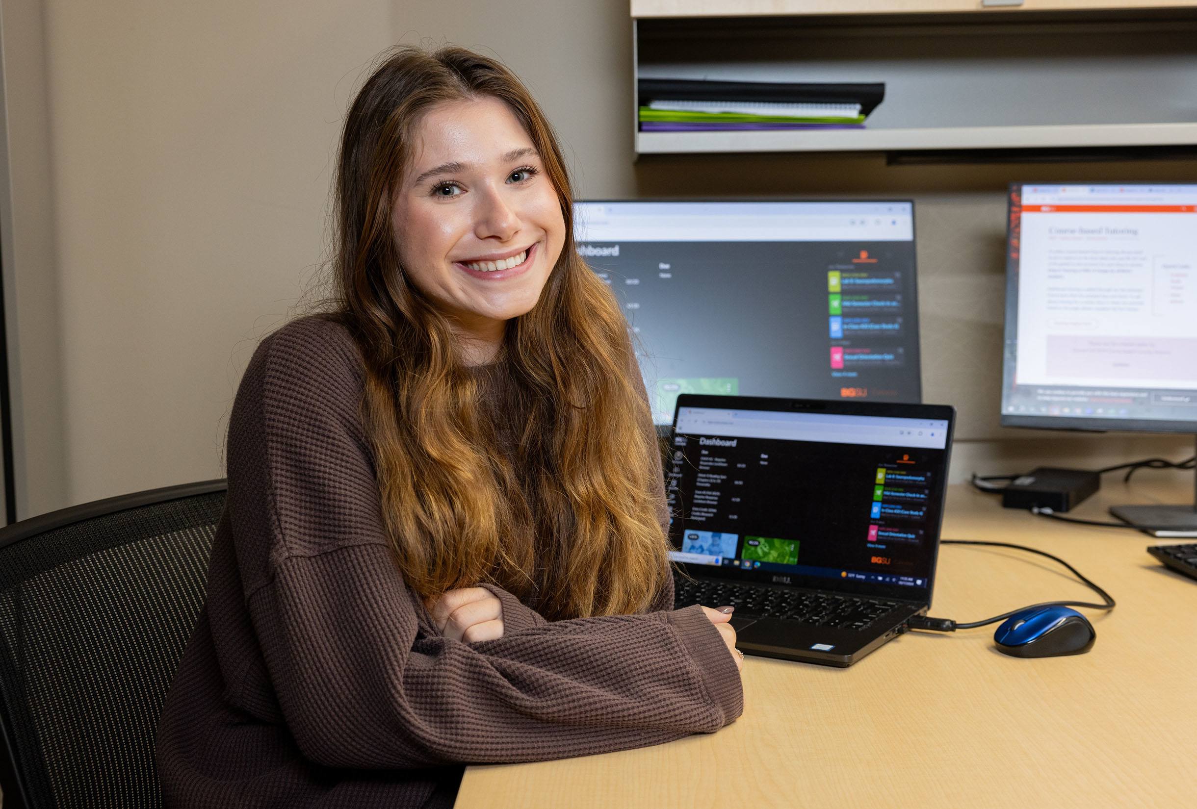 BGSU student Taylor Gaies smiles in front of her computer.