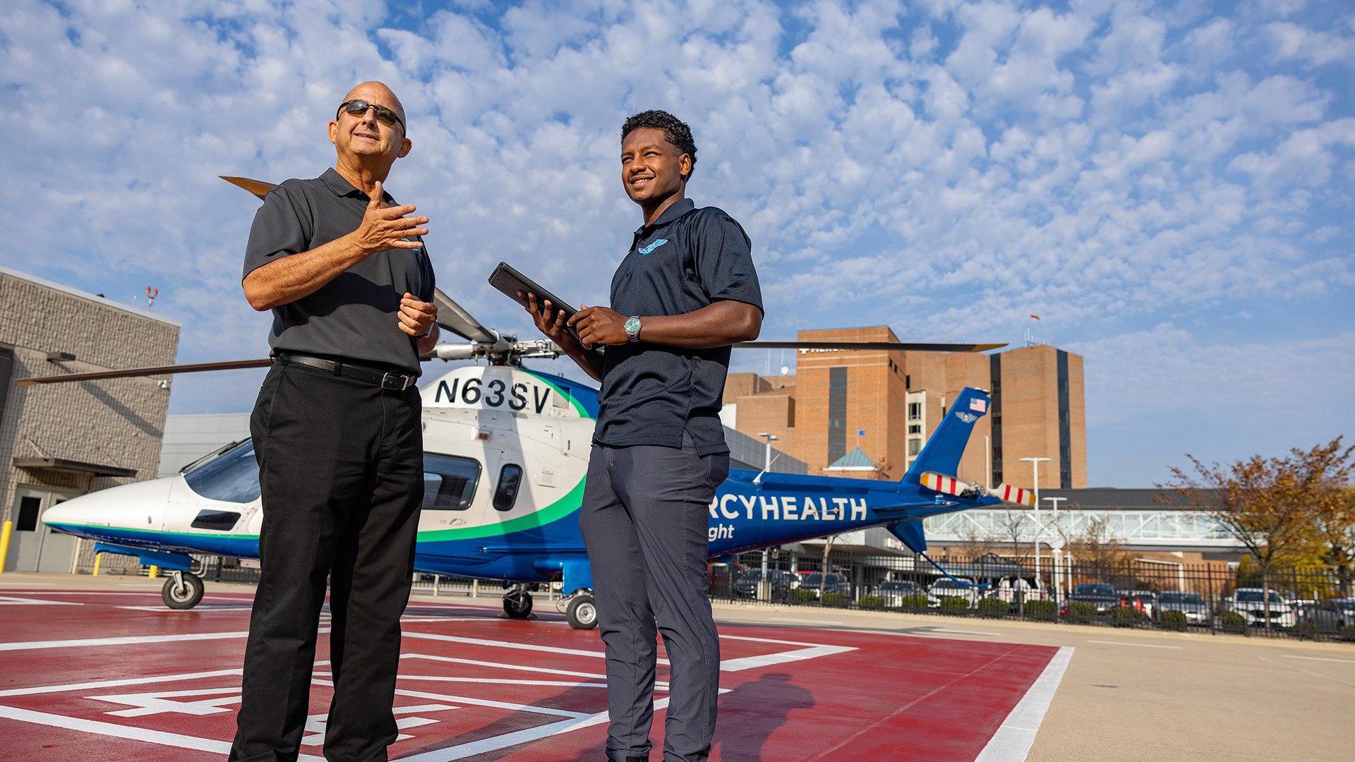 Two people stand in front of a medical helicopter.