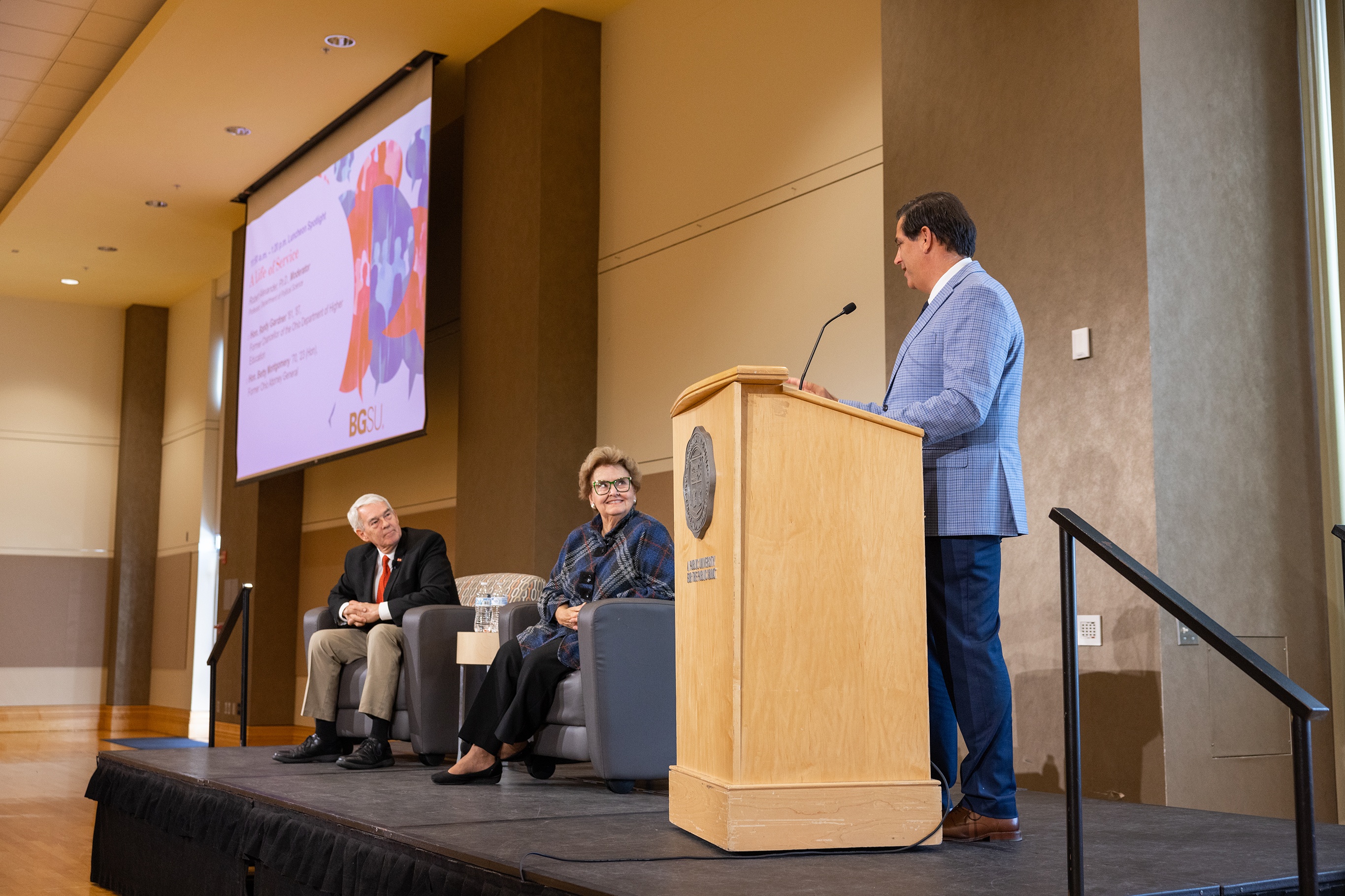 Three people speaking on a stage