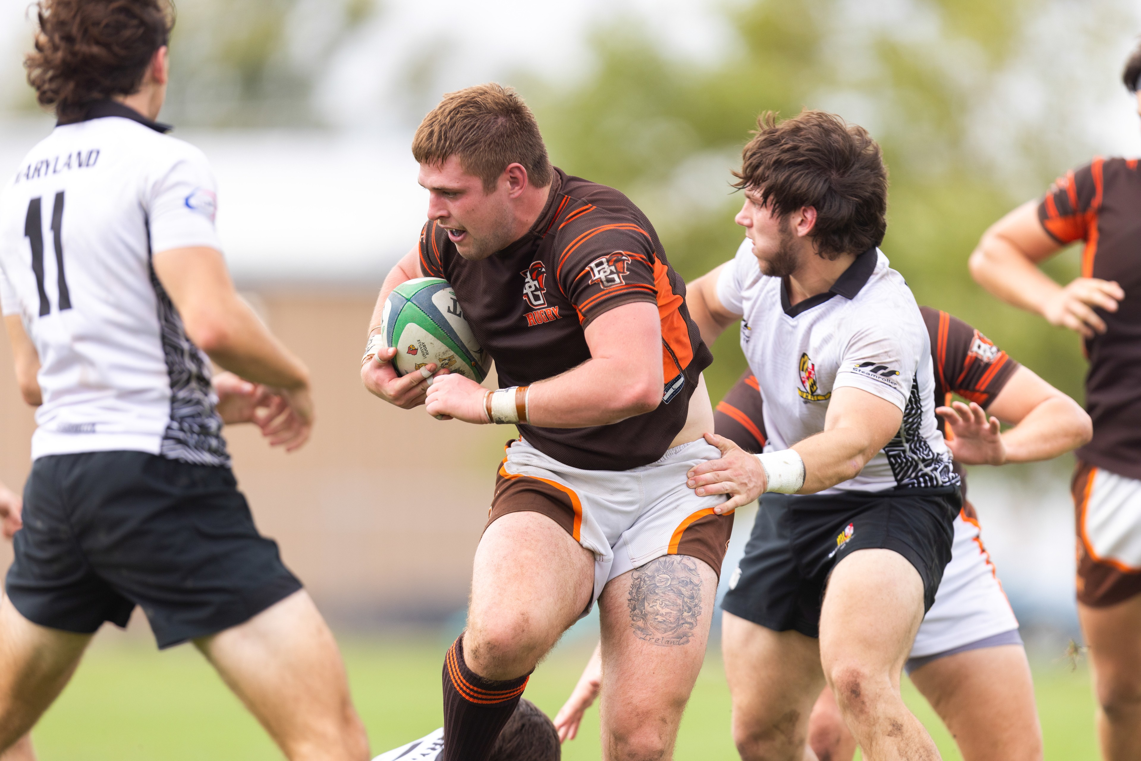 A rugby player carries the ball downfield.