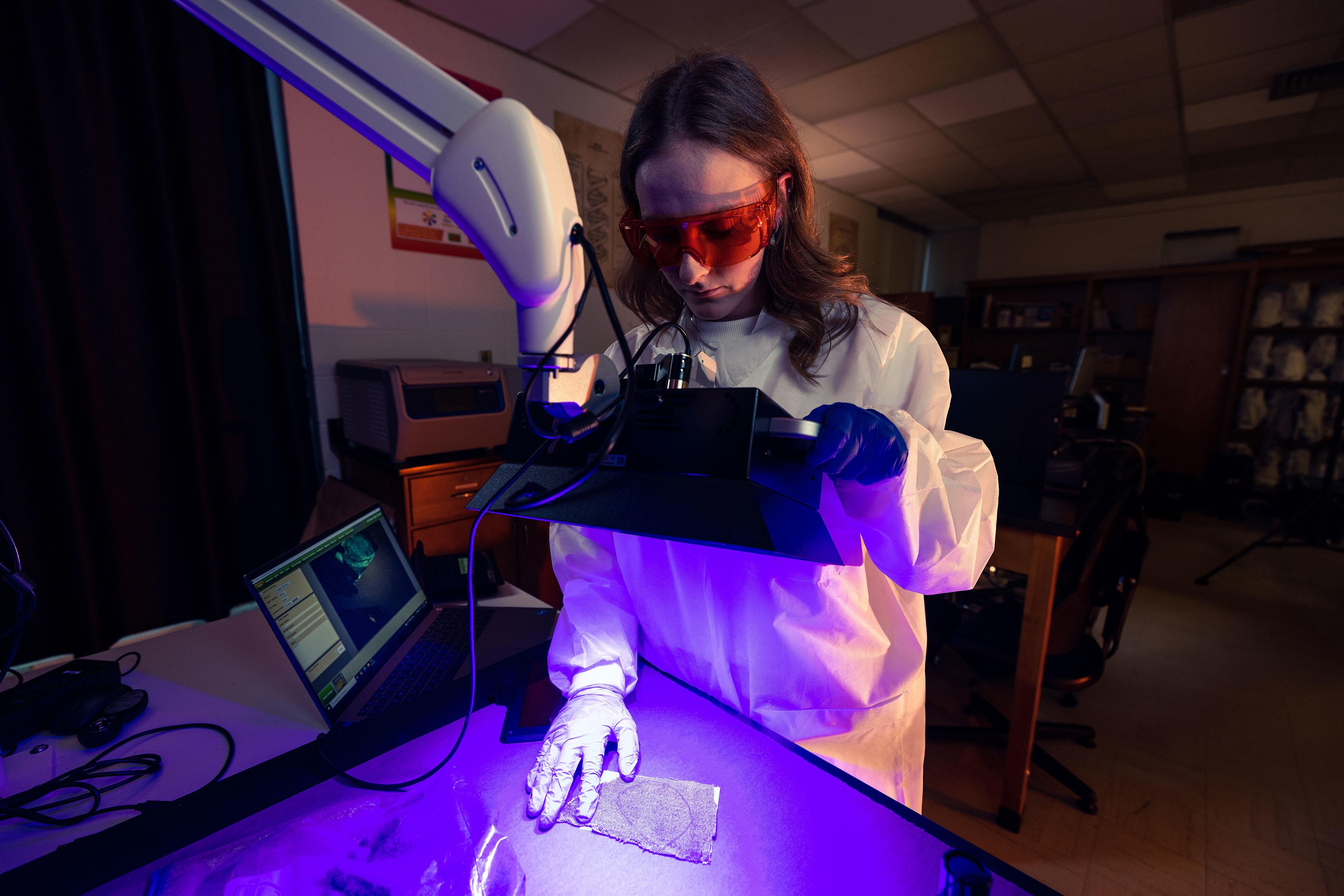 A BGSU student uses light to examine mock evidence.