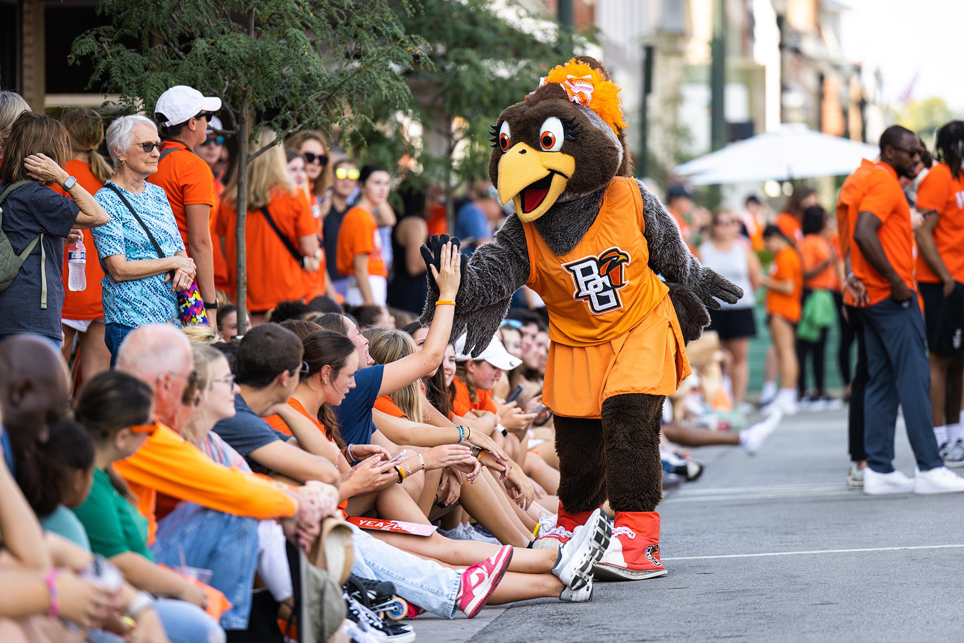 A falcon mascot gives high fives to kids