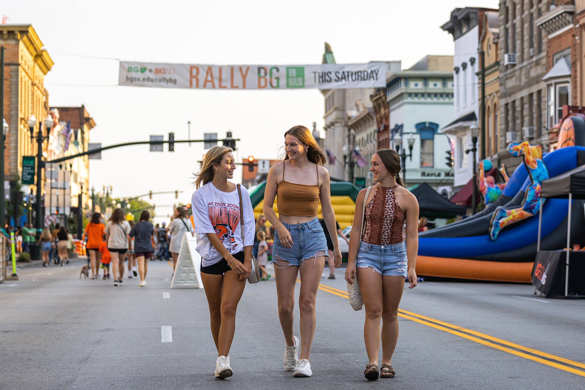 Three students walk down a street during a festival