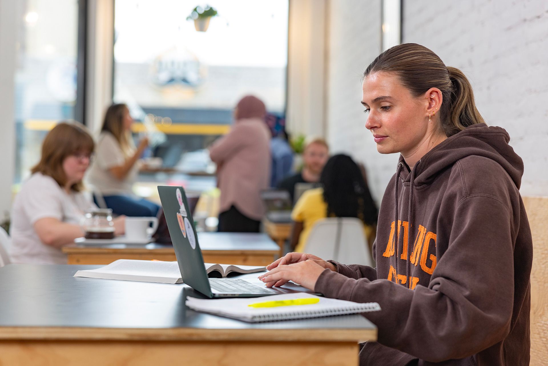 A person works on a laptop in a coffee shop.