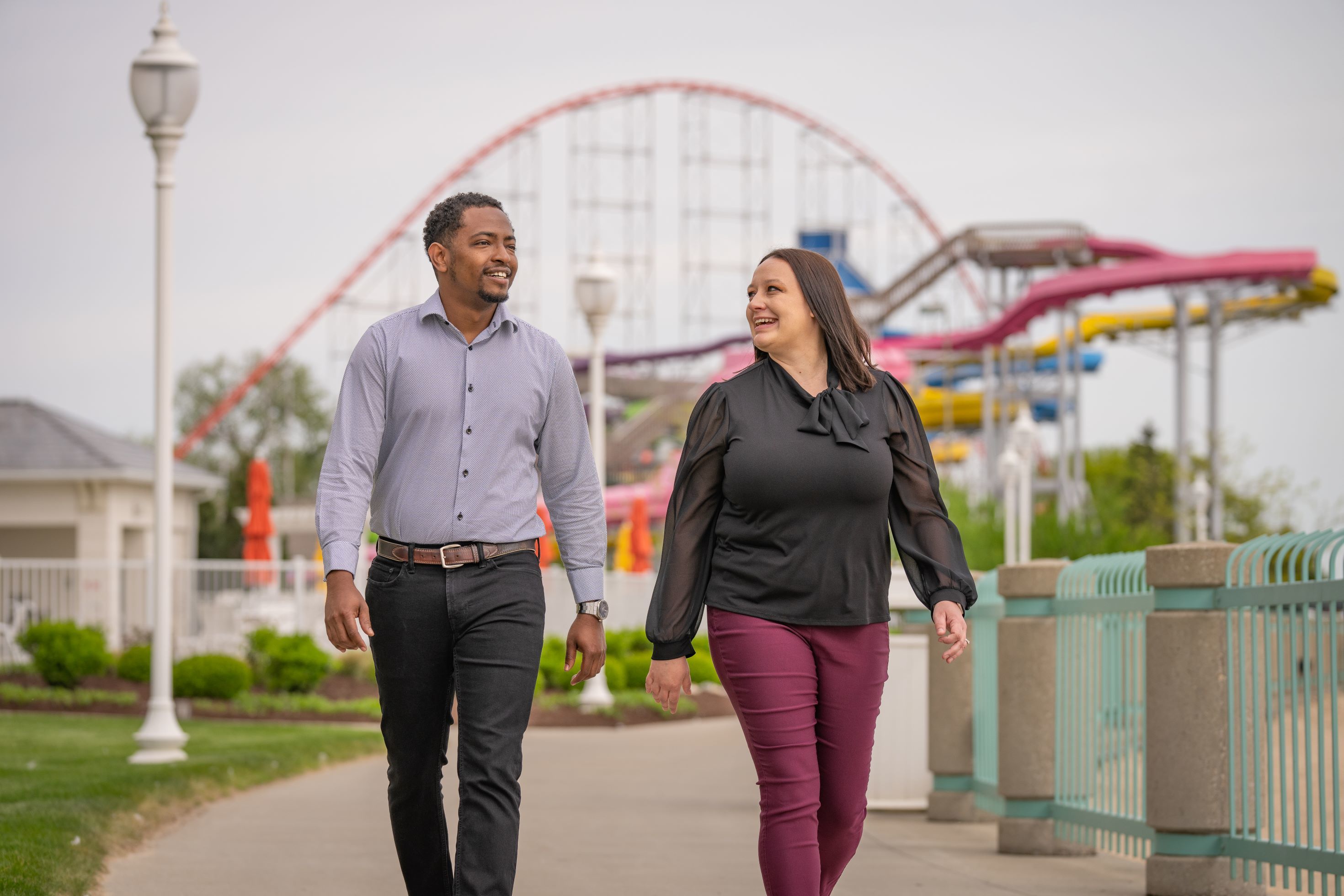 Two people walk in an amusement park.