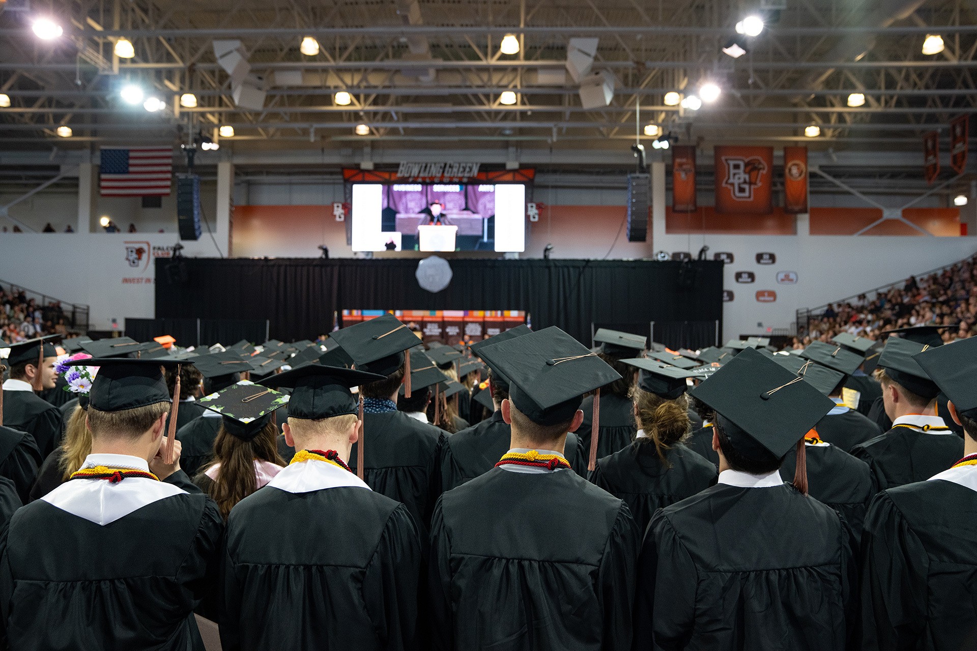 A group of students in caps and gowns facing a stage