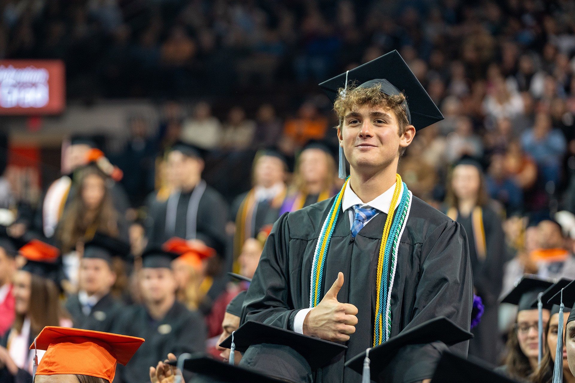 A smiling person in a cap and gown