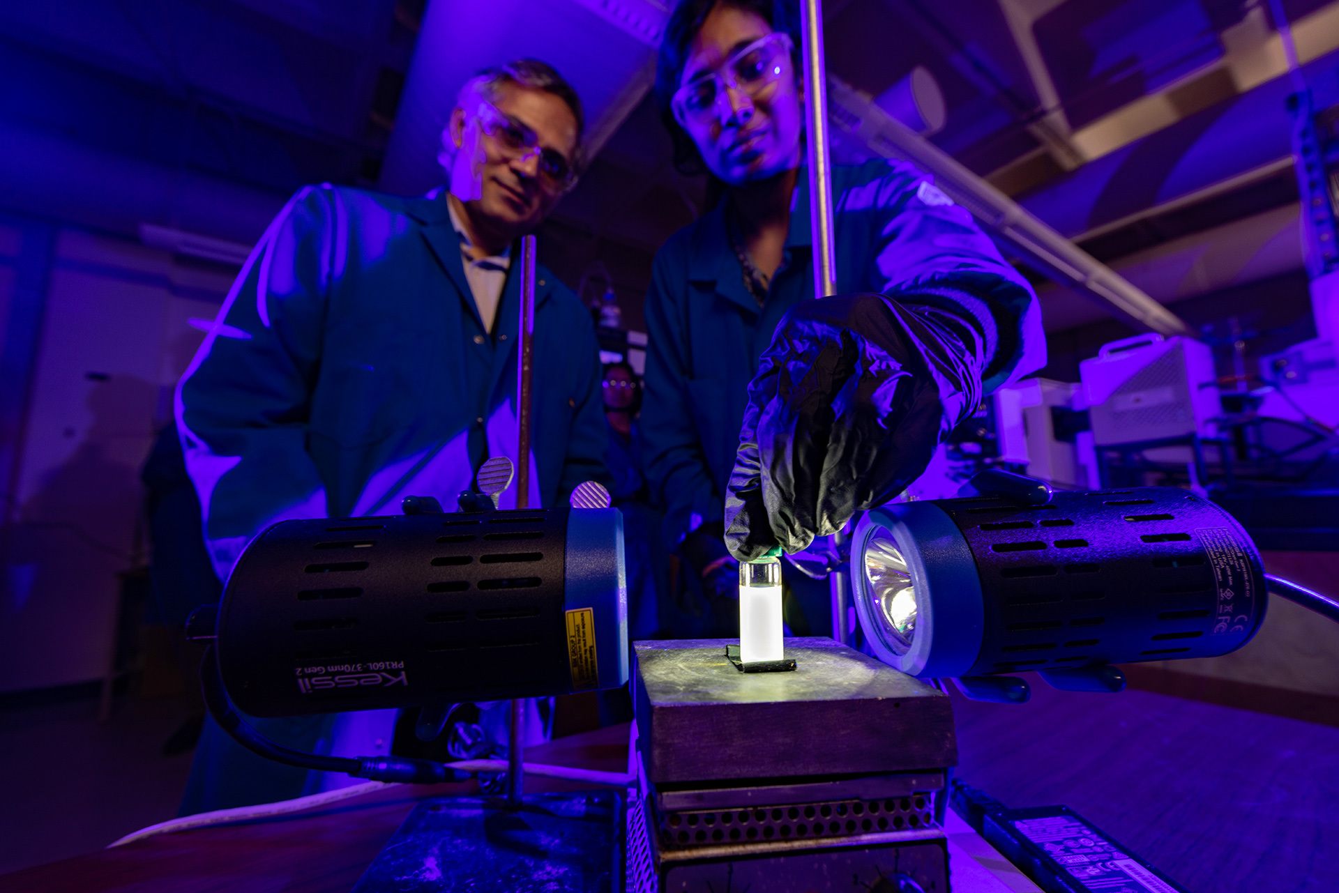 Two researchers examine a vial.