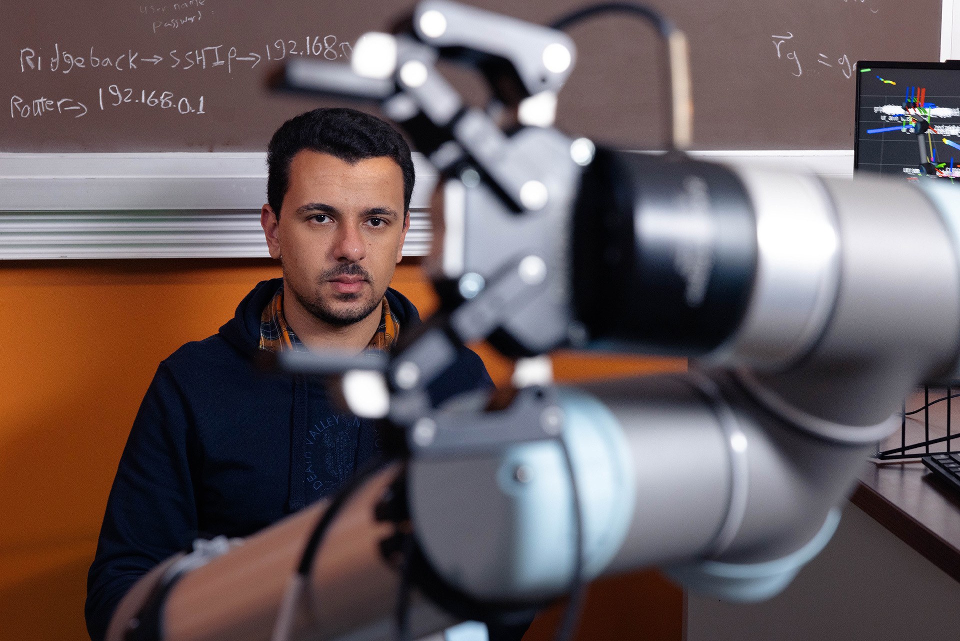 Man's face is seen through the claw of a robotic arm