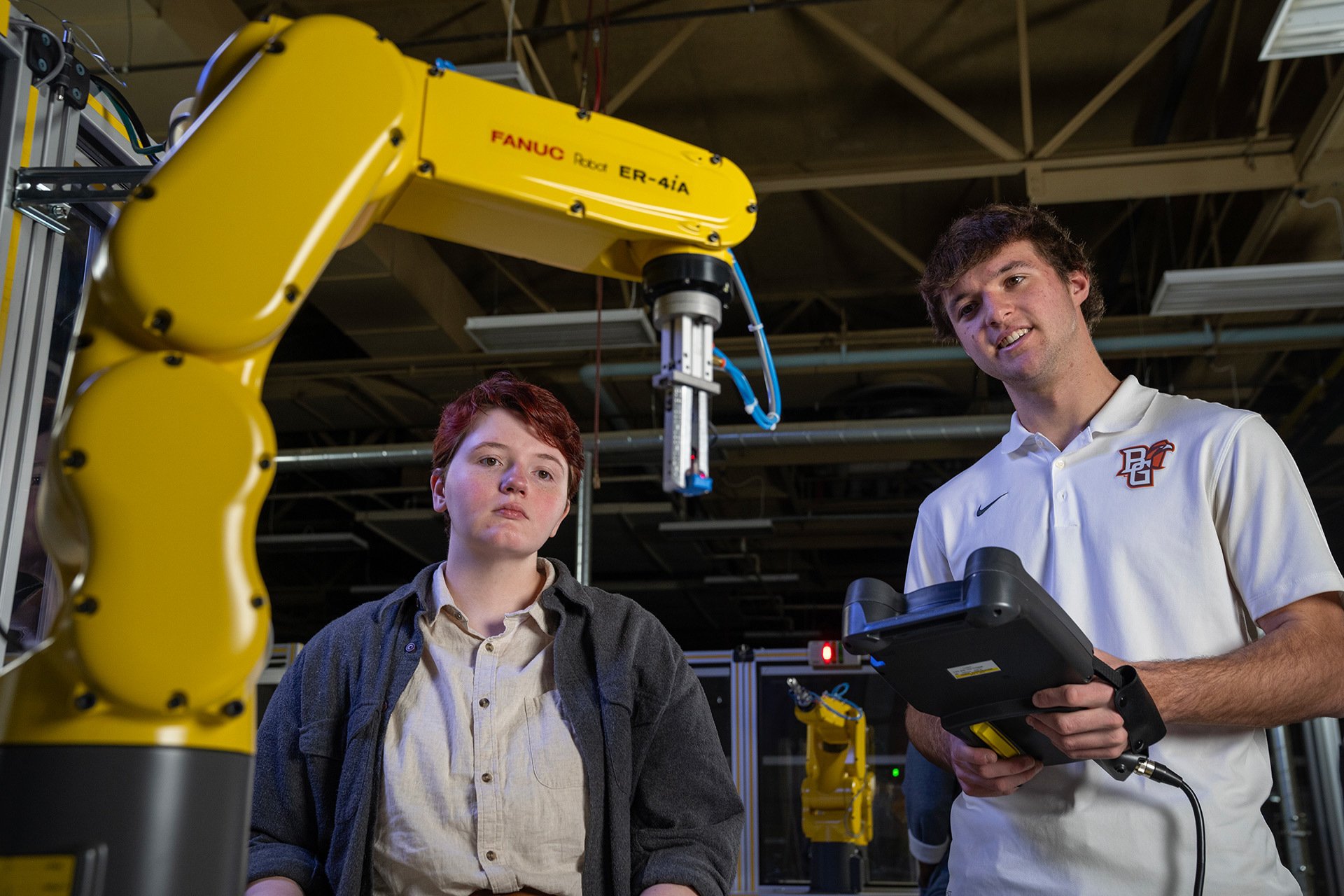 Two BGSU students work with a FANUC robot. 