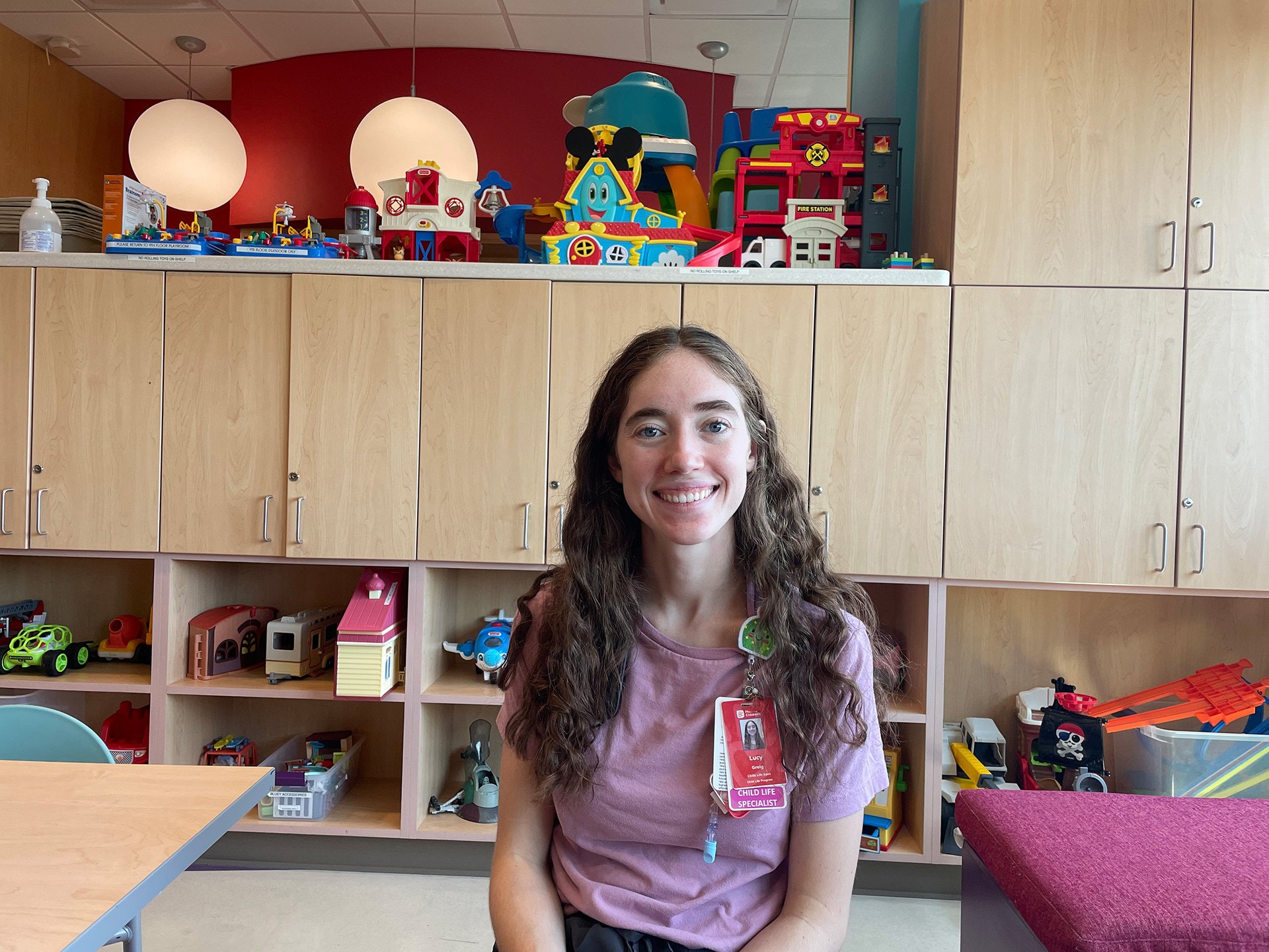 A person sits in a room surrounded by toys.