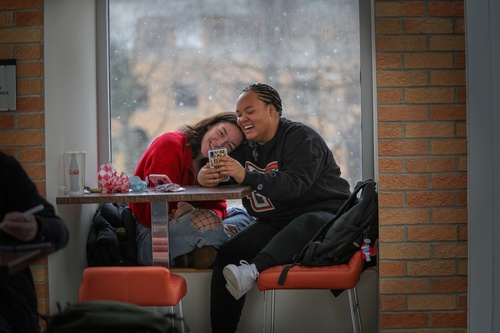 Two students enjoying social media during lunch