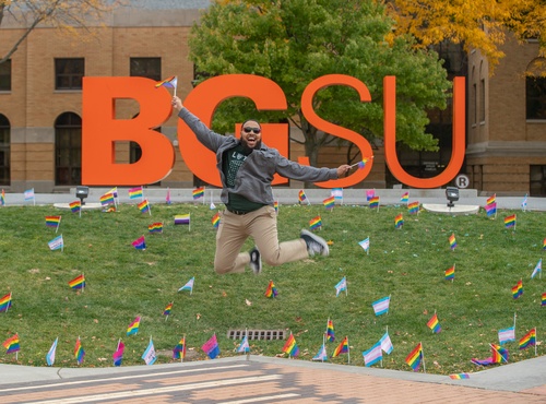 An individual jumping holding pride flags