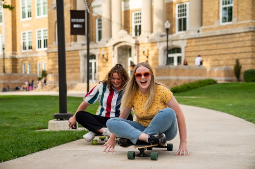 Two students skateboarding outside