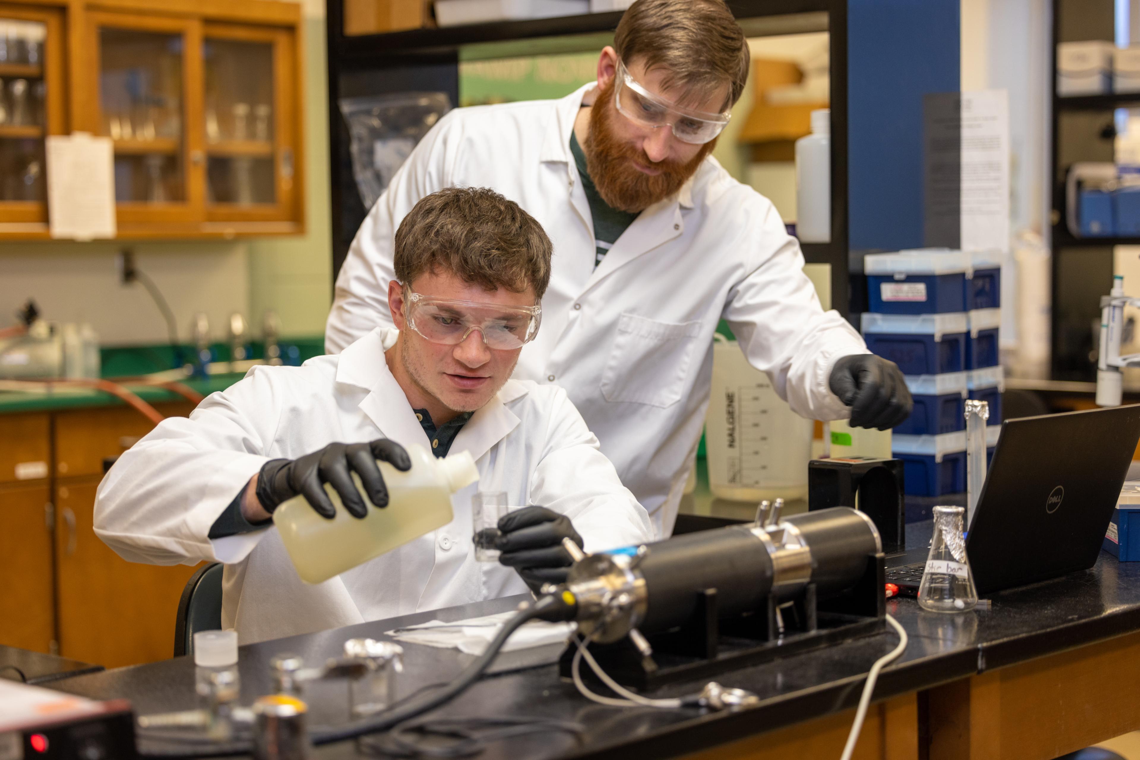 Two students measure chemicals in the lab