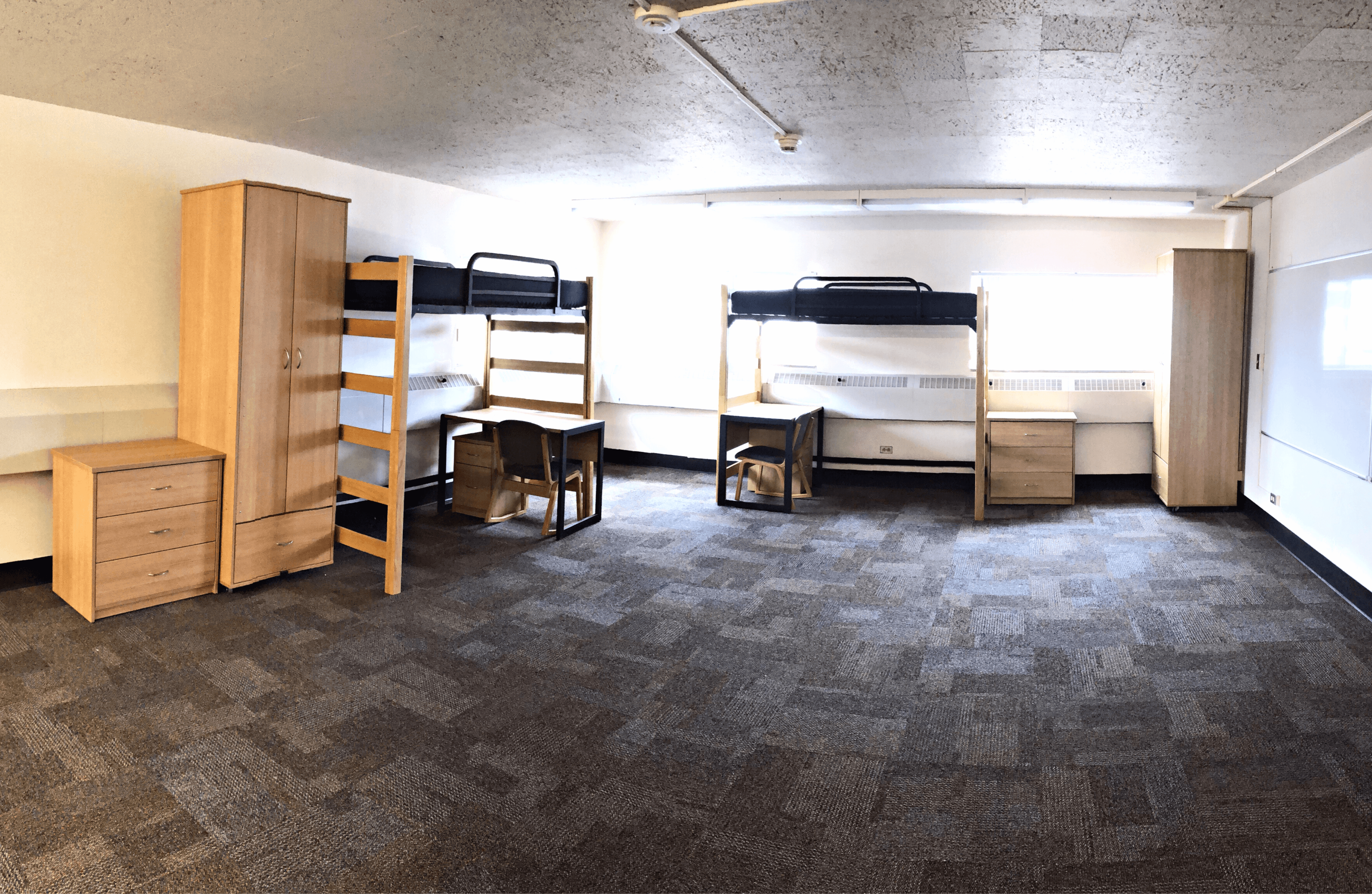 Two beds, dressers, desks and wardrobe, right side of the room