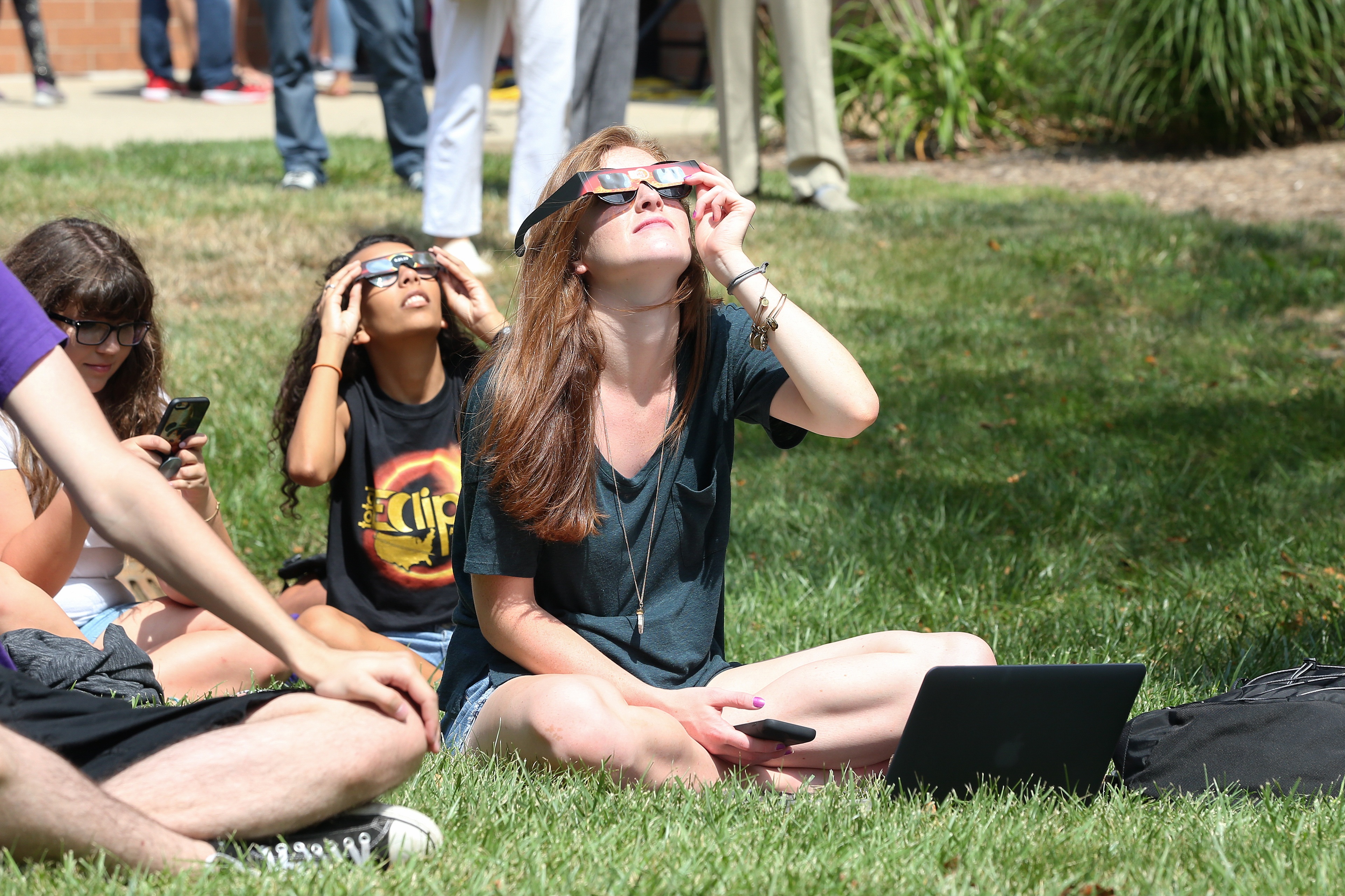 Students in grass with eclipse glasses on